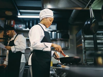 Below view of black female chef preparing food at restaurant.