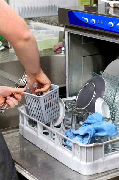 Restaurant kitchen worker emptying a dishwasher